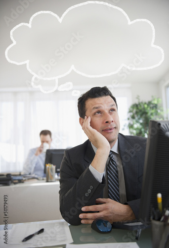 Mixed race businessman sitting under thought bubble photo