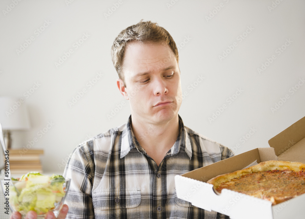 Caucasian man looking at pizza in box Caucasian man looking at pizza in box