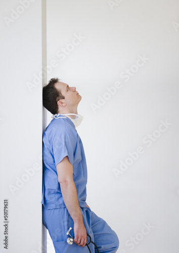 Caucasian surgeon leaning against wall