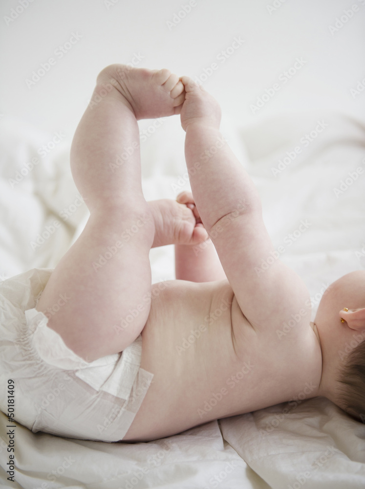 Caucasian baby girl laying on blanket holding feet Caucasian baby girl laying on blanket holding feet
