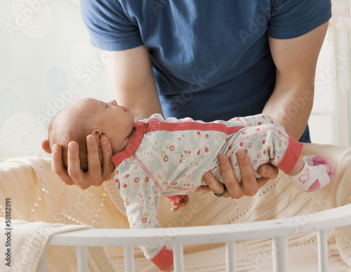 Caucasian father lifting baby girl from crib photo