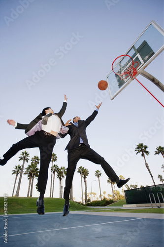 Businessmen playing basketball outdoors photo