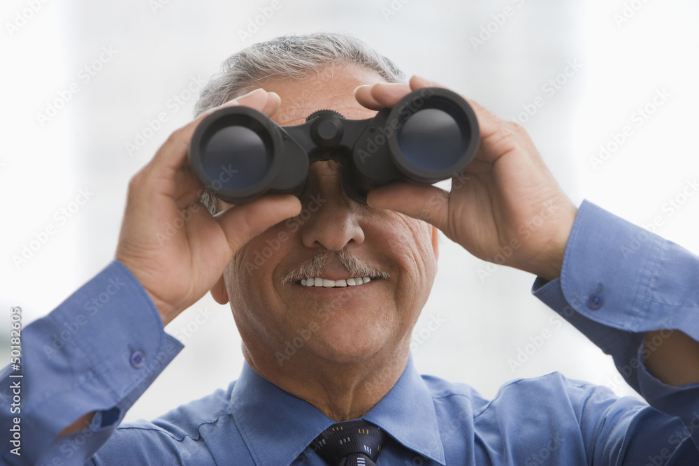 Hispanic businessman using binoculars Hispanic businessman using binoculars