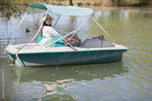 Happy young woman having fun in a pedal boat in a lake