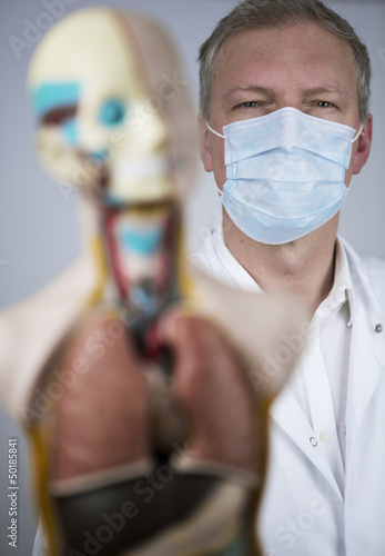 arzt mit anatomischer figur und mundschutz photo