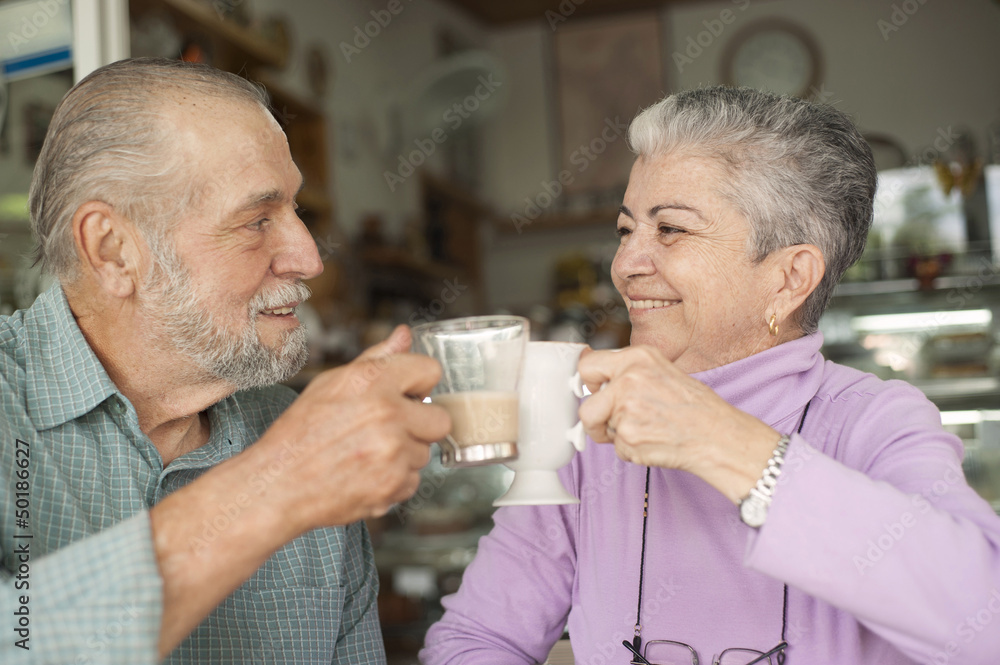 Hispanic couple toasting with coffee cups in cafe Hispanic couple toasting with coffee cups in cafe