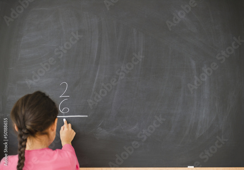 Mixed race girl doing math on blackboard