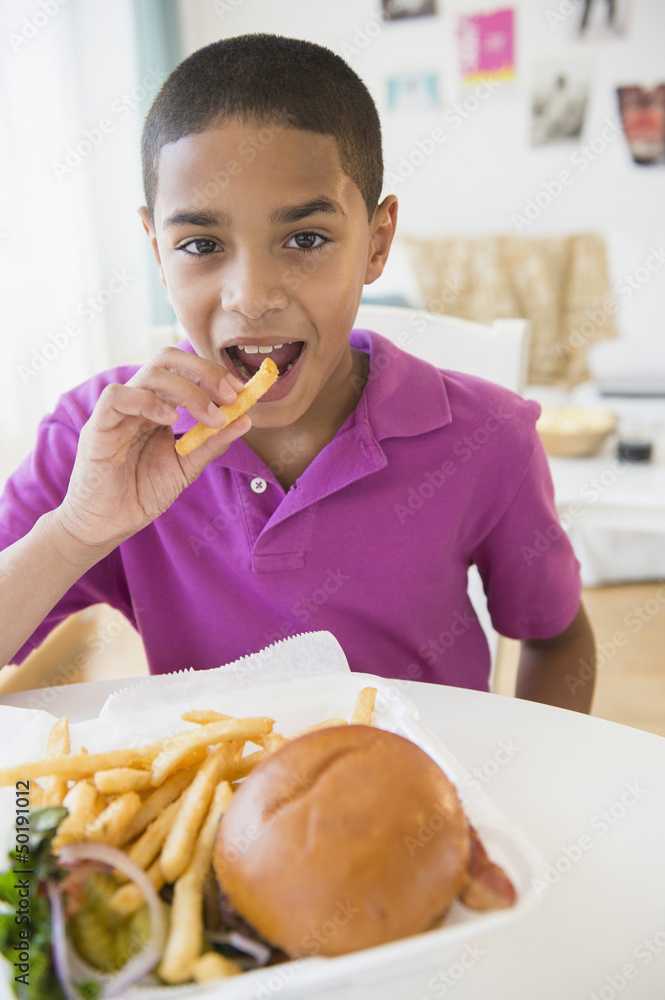 Hispanic boy eating hamburger and french fries Hispanic boy eating hamburger and french fries