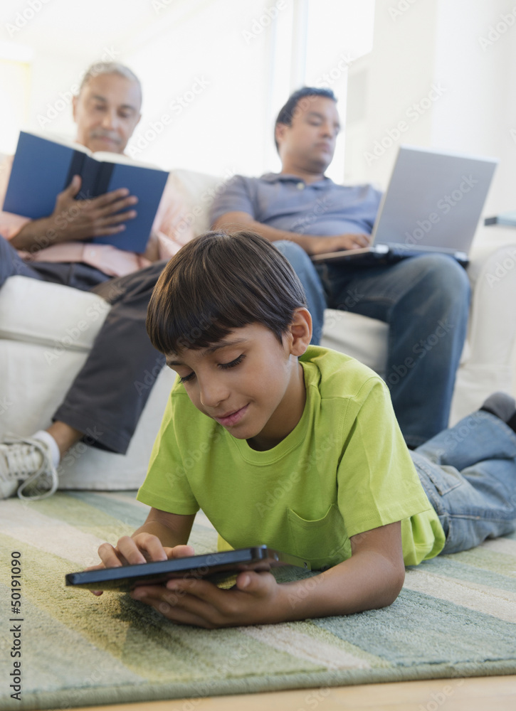 Hispanic boy laying on floor using digital tablet Hispanic boy laying on floor using digital tablet