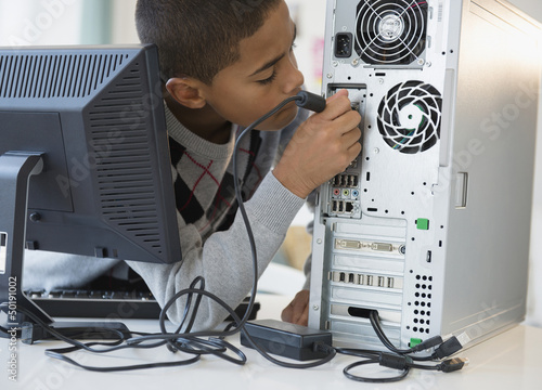 Hispanic boy plugging in computer