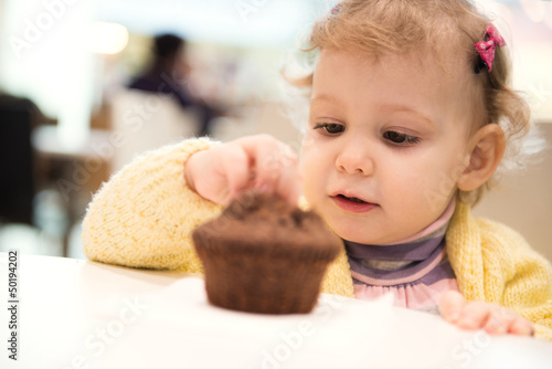 Cute girl eating muffins in cafe