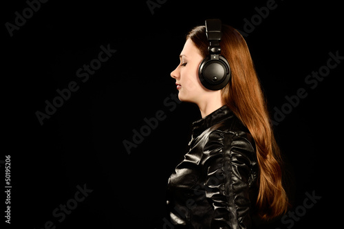 Attractive young girl with big headphones on black background