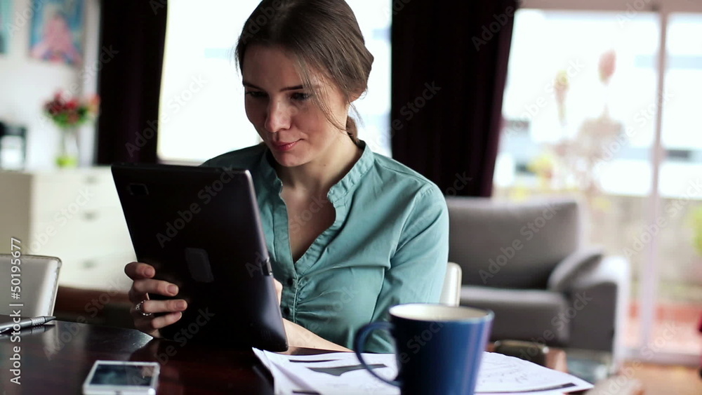 Businesswoman working on tablet computer in home Businesswoman working on tablet computer in home