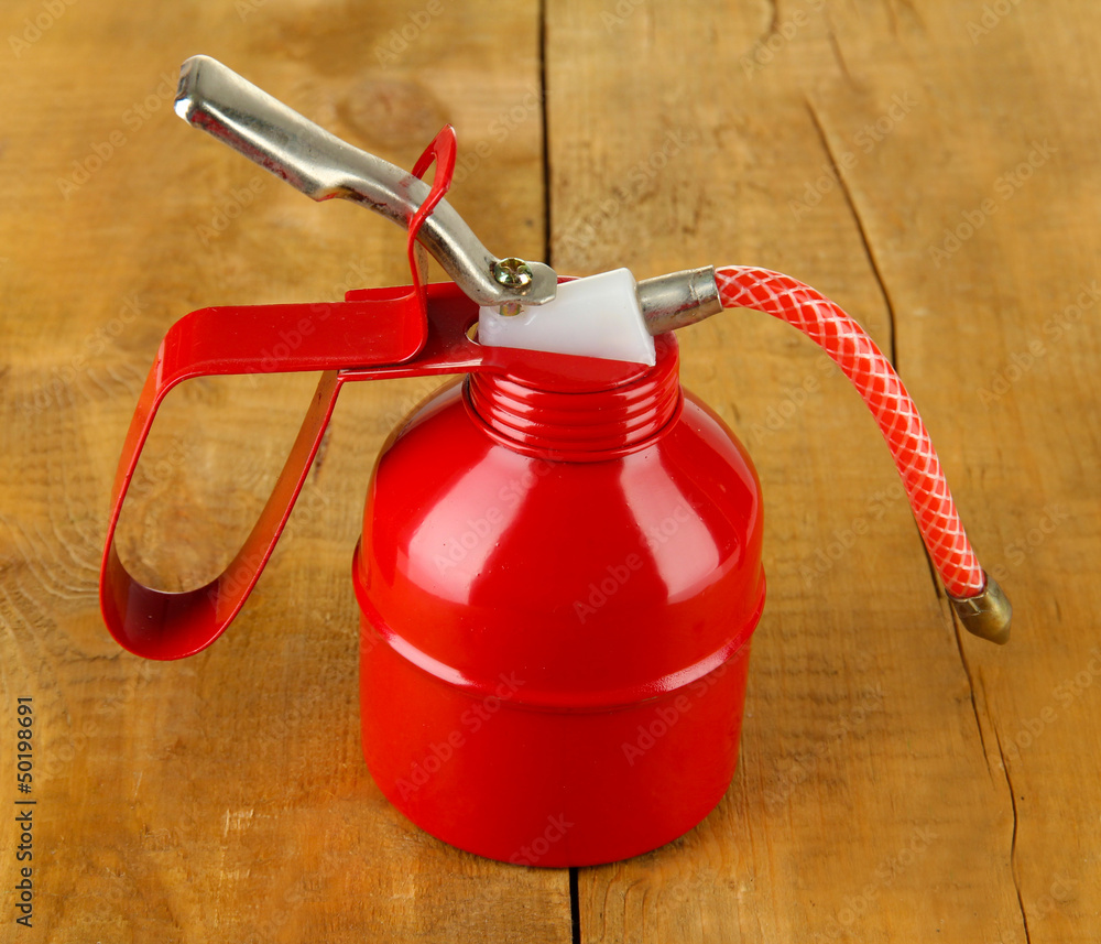 Naklejka premium Red oil can, on wooden background