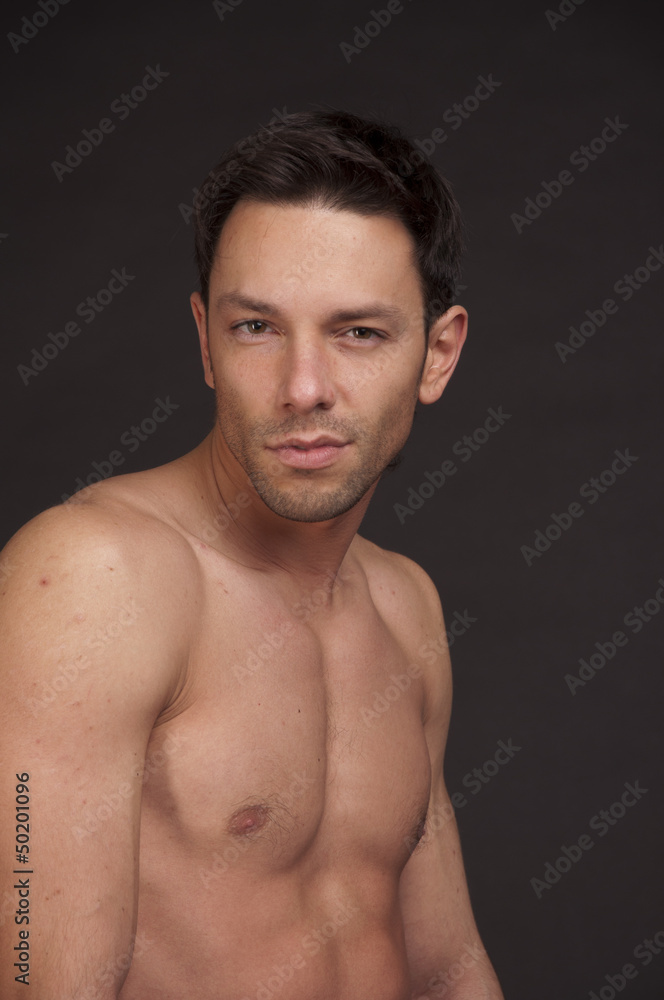 Young attractive guy without a shirt. Handsome naked man posing in studio. Atelt. Fitness and healthy lifestyle.