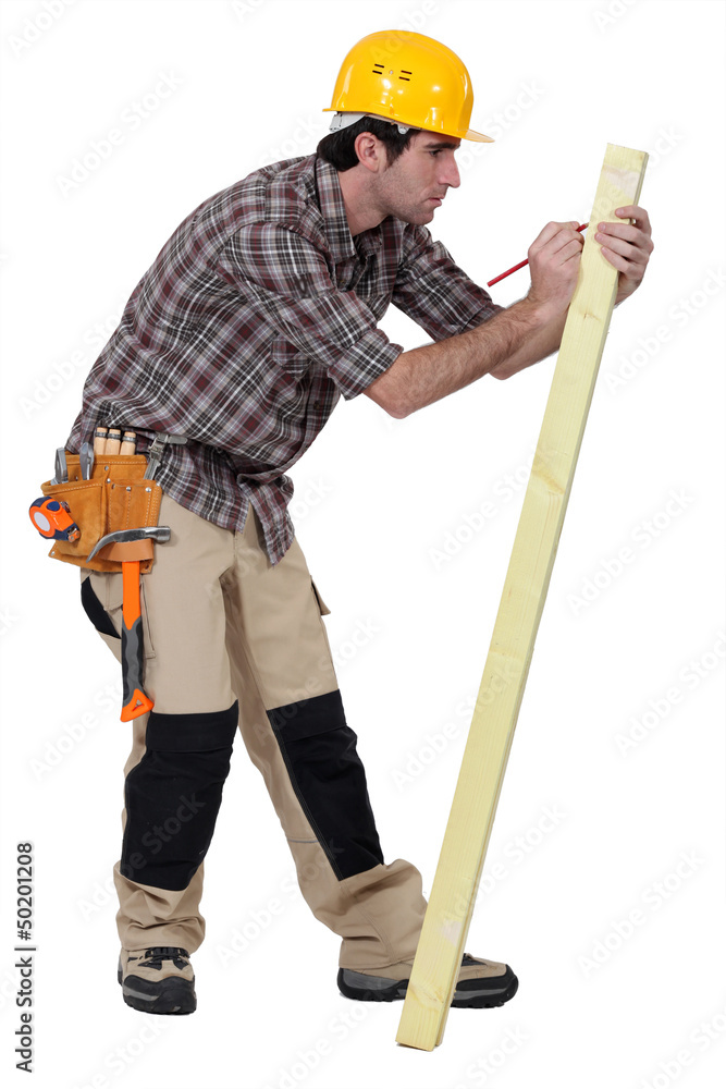 Man marking a measurement on a wooden plank Man marking a measurement on a wooden plank