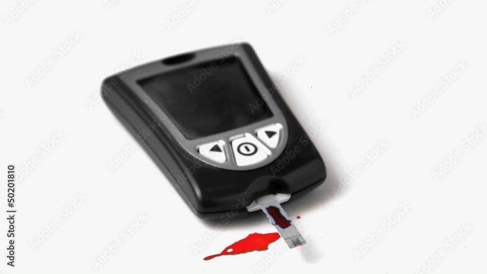 Drop of blood falling onto test strip of blood glucose monitor Drop of blood falling onto test strip of blood glucose monitor