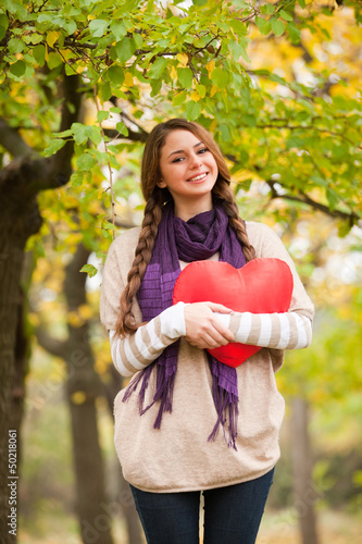 Girl with toy heart at autumn park.