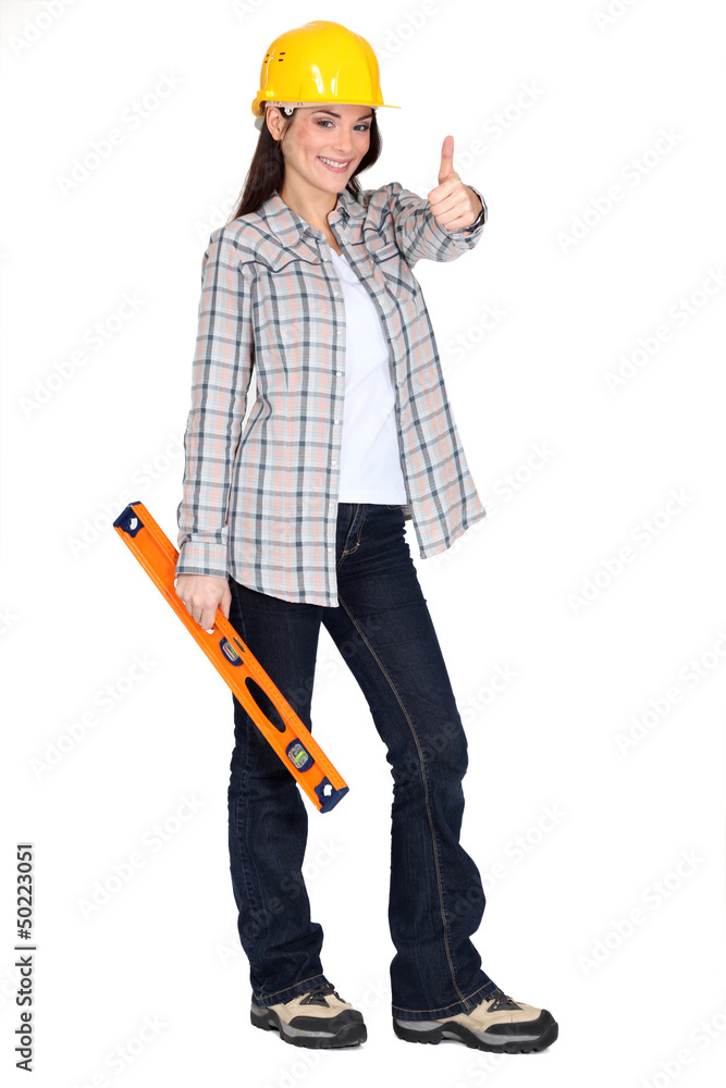 Woman holding spirit-level and giving the thumbs-up Woman holding spirit-level and giving the thumbs-up