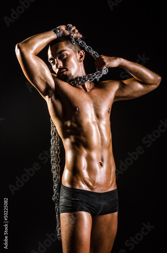 Muscular man with chain on black background © Elnur