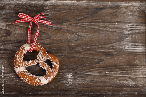 Brezel mit rotweißer Schleife auf Holzbrett - pretzel on wood photo