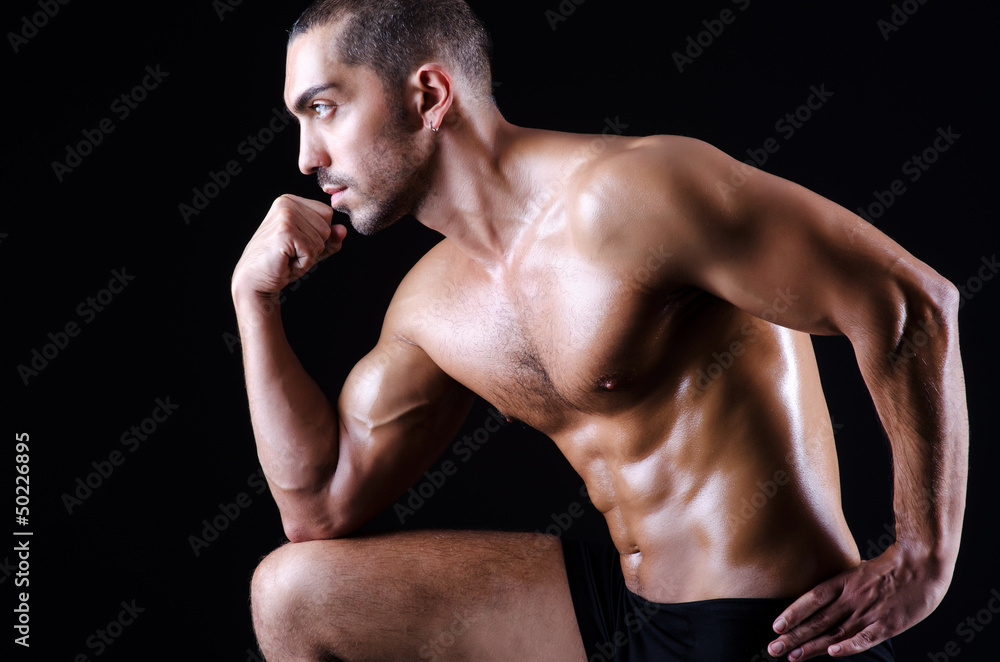Muscular man in dark studio Muscular man in dark studio