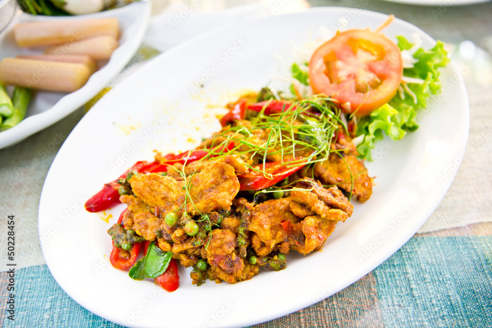 Dried pork with spicy curry on white plate in restaurant