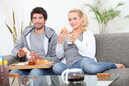 Couple having breakfast on couch