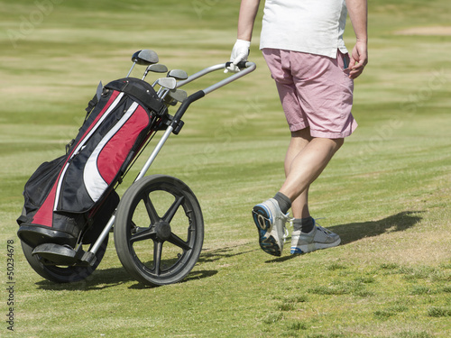 Golfer walking on course with bag