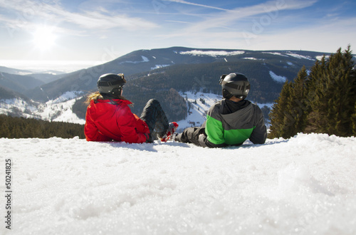 Young happy couple lying in snowy mountains. Winter sport