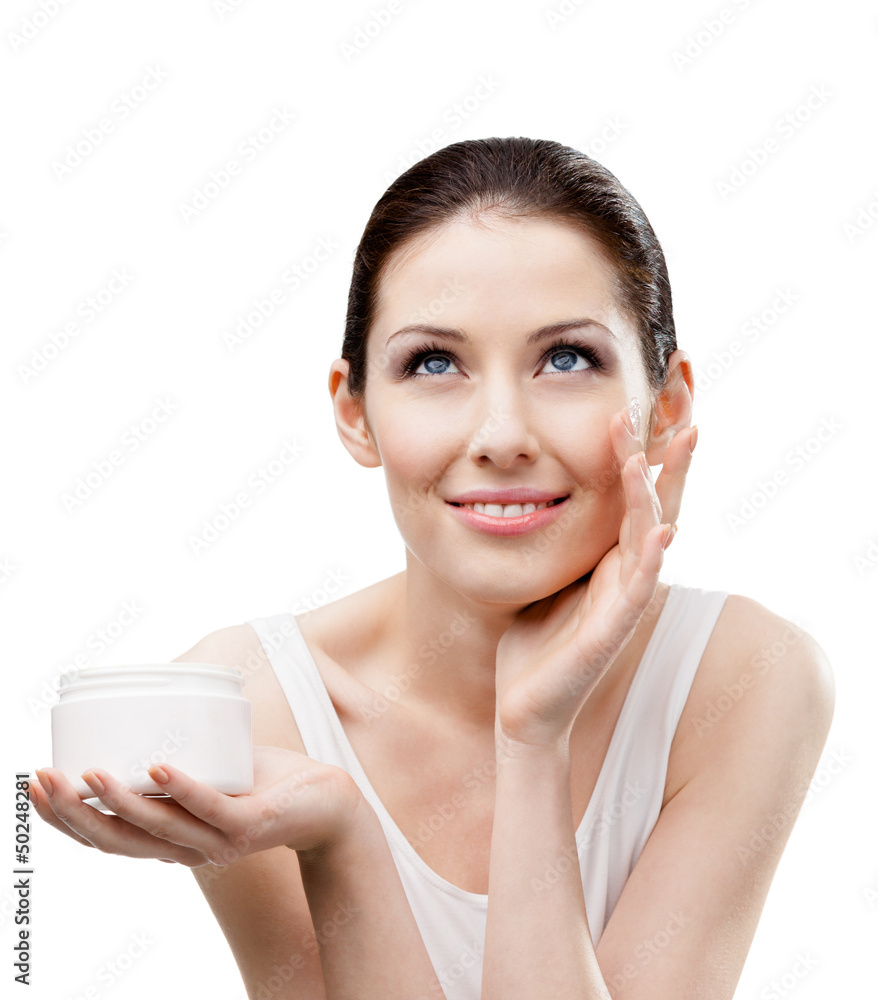 Woman putting on moisture cream from container on face Woman putting on moisture cream from container on face