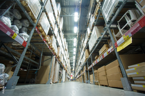 Rows of shelves with boxes and other goods in modern warehouse