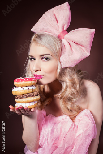 Donuts. Funny woman eating donuts smiling in studio