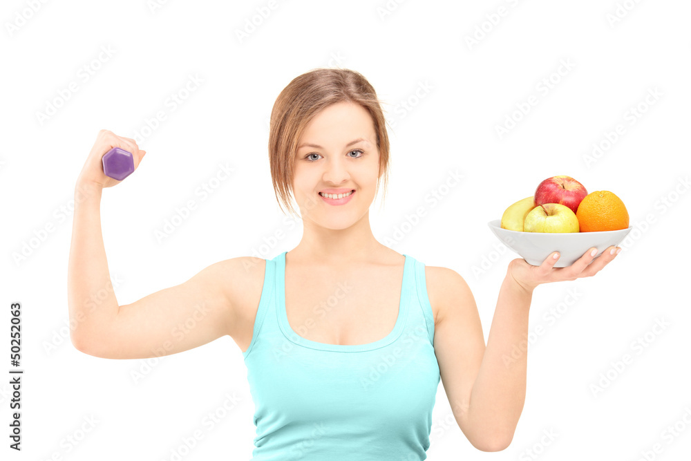 Beautiful young female posing with a dumbbell and fruits in a bo Beautiful young female posing with a dumbbell and fruits in a bo