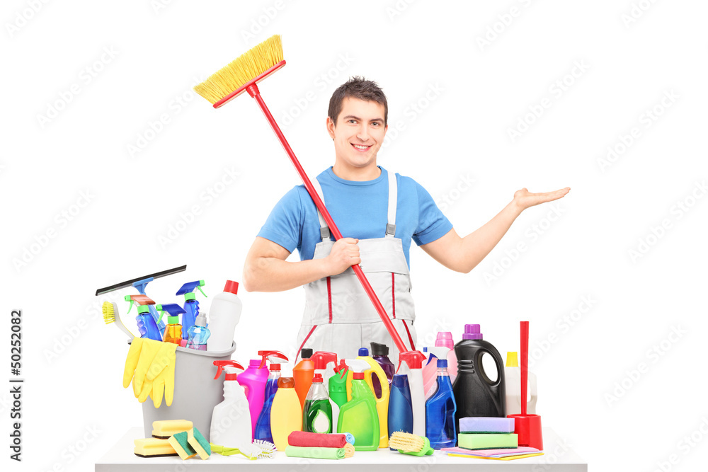 Man in a uniform holding a broom and posing with cleaning suppli Man in a uniform holding a broom and posing with cleaning suppli