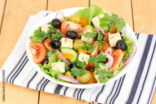 Fresh salad in plate on wooden table