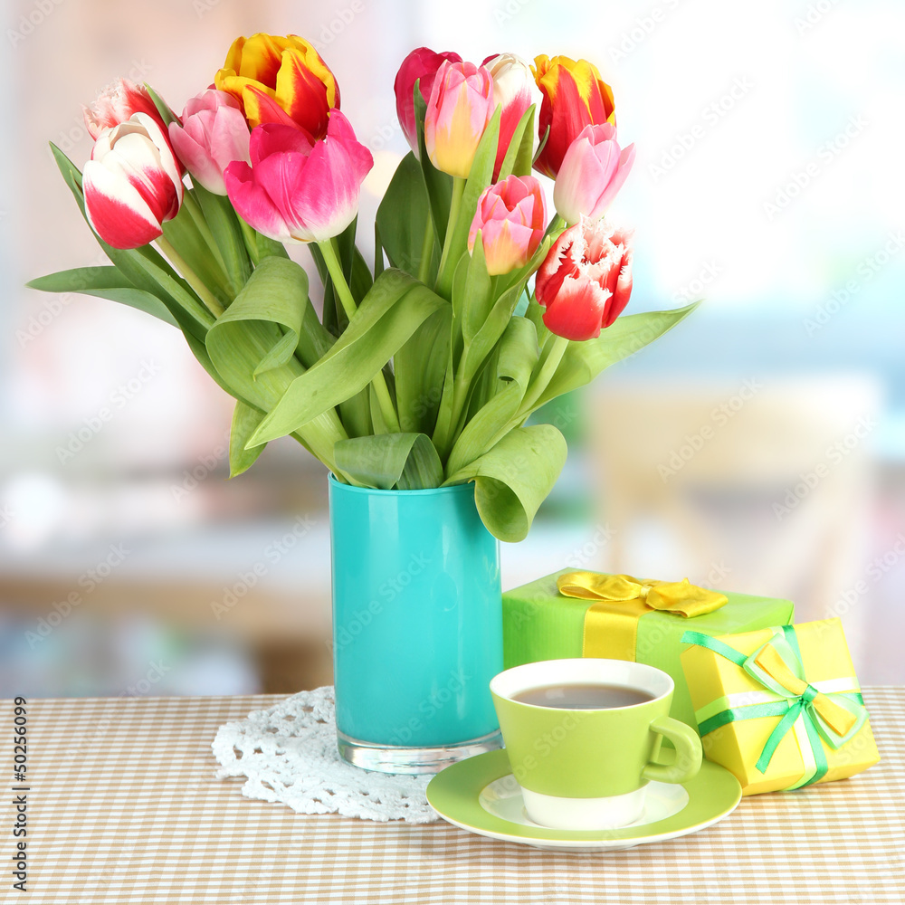 Beautiful tulips in bucket with gifts and cup of tea