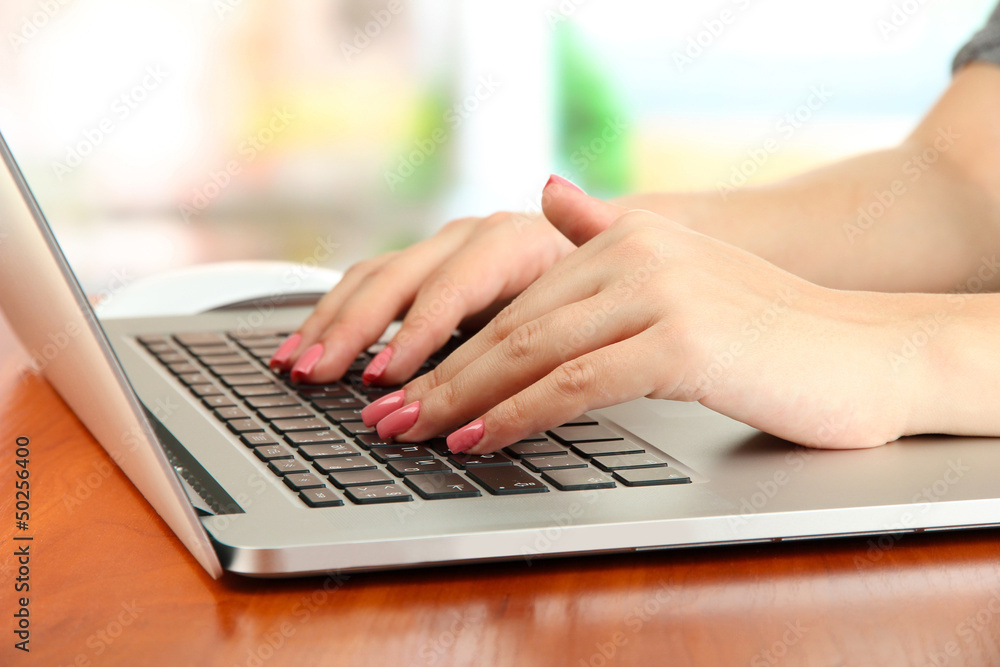 Female hands writing on laptop, on bright background Female hands writing on laptop, on bright background