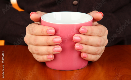 Hands holding mug of hot drink, close-up
