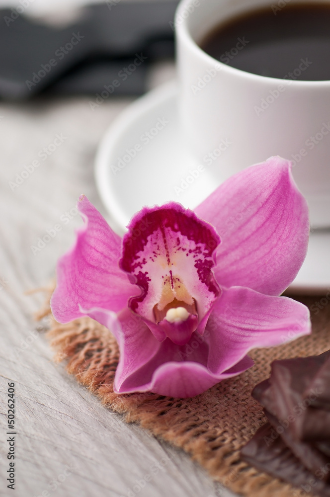 cup of coffee, chocolate and orchid on wooden background cup of coffee, chocolate and orchid on wooden background