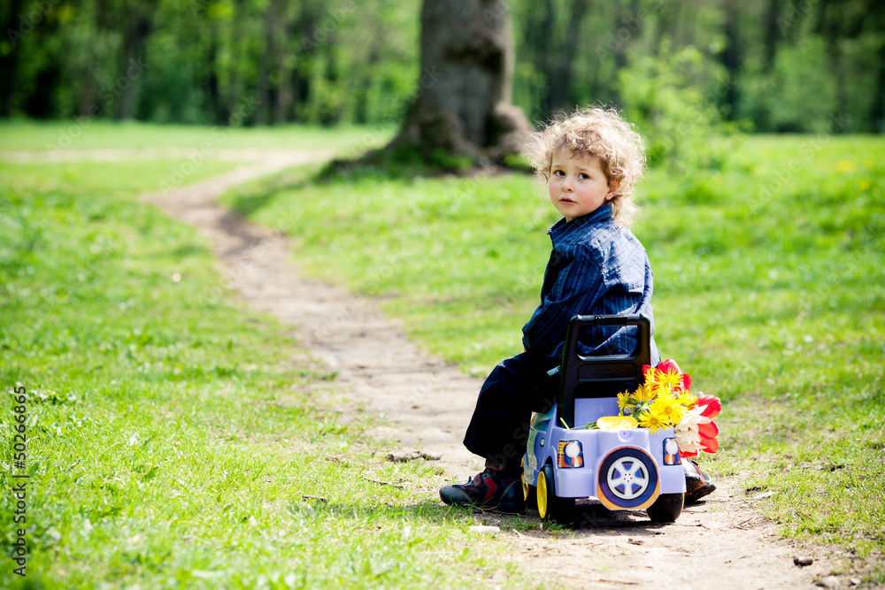 little boy on a toy-car in park little boy on a toy-car in park