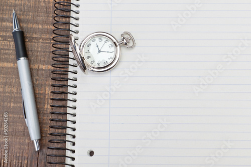 Photography Antique pocket watch on notebook for notes. On textured wood.