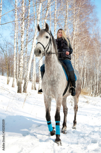 Girl riding on pale horse sunny winter