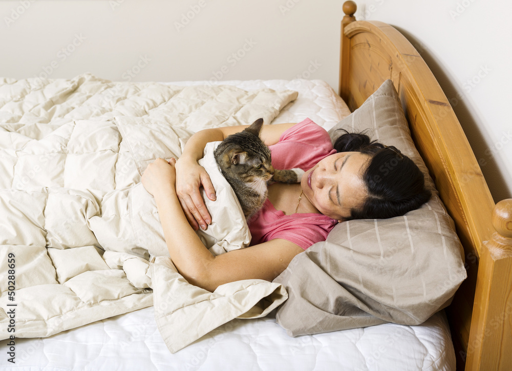 Mature woman looking at her cat while trying to sleep Mature woman looking at her cat while trying to sleep