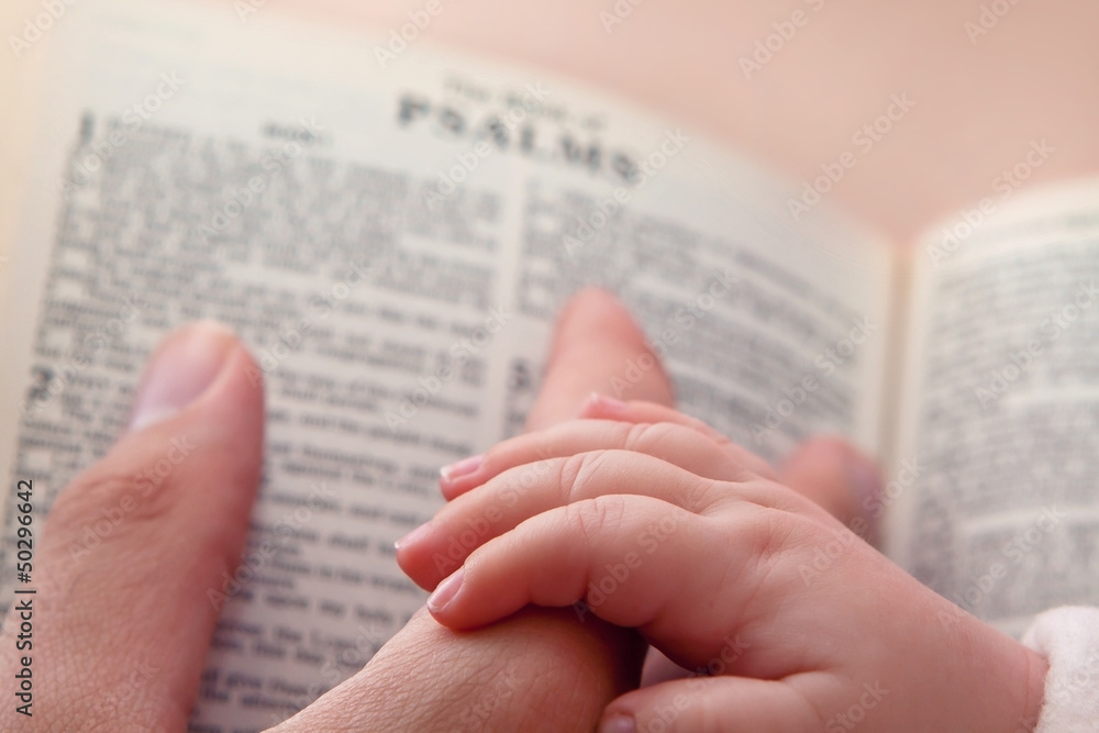 Obraz premium Baby Holding Dad’s Finger on Bible