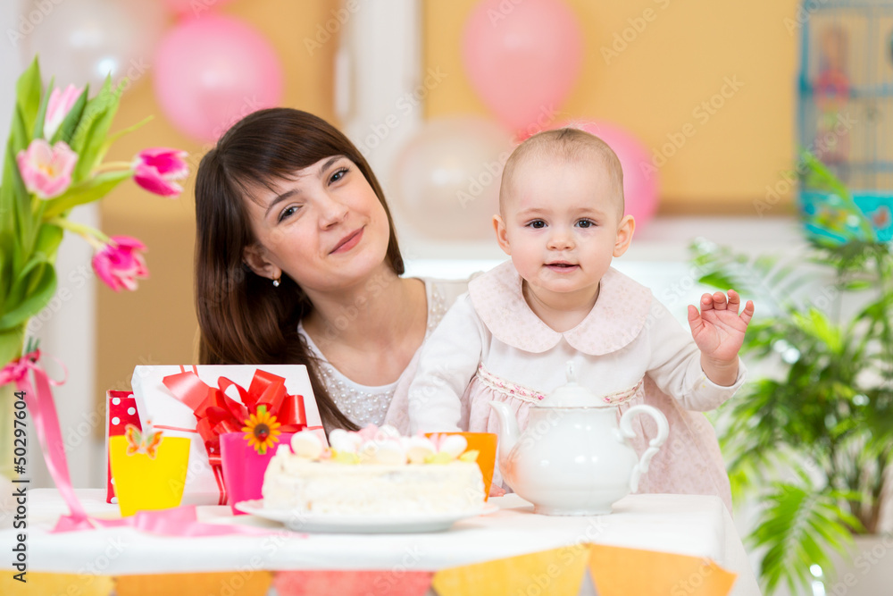 Little girl and mother celebrate birthday holiday. Focus at baby