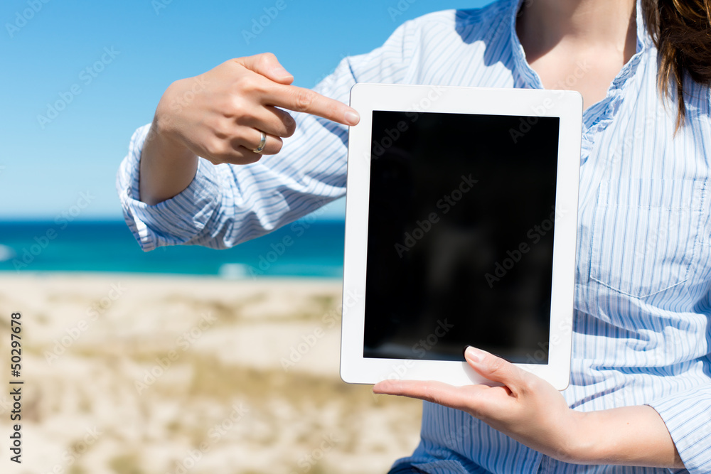 frau am strand zeigt auf tablet-pc