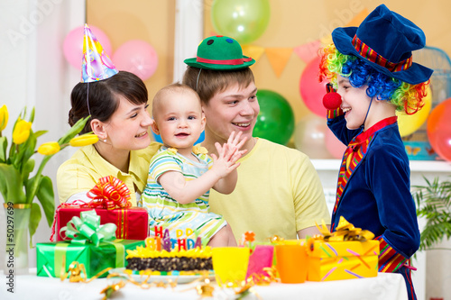 baby girl celebrating first birthday with parents and clown