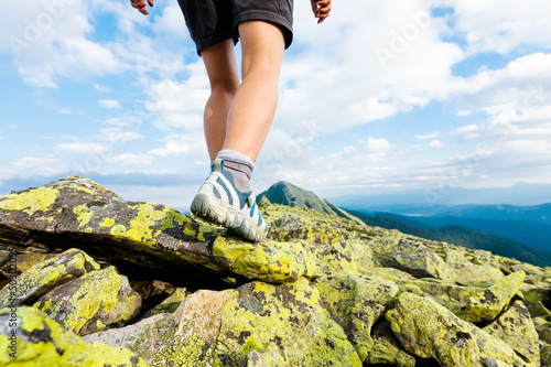Hiker makes her way over the stones in mountains. Foot closeup
