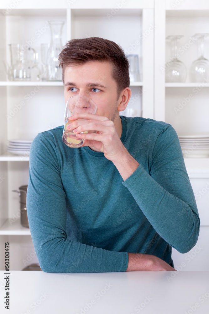young man drinking refreshing lemonade in his kitchen